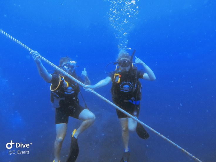 Two scuba divers pose on a mooring line
