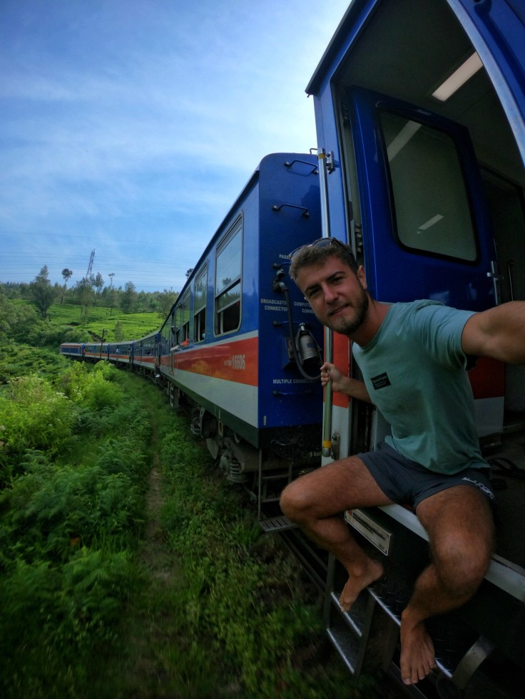 Tourist takes photo out the door of the Ella to Kandy Train