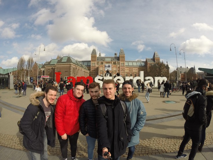 5 male friends take a selfie in front of the Amsterdam sign